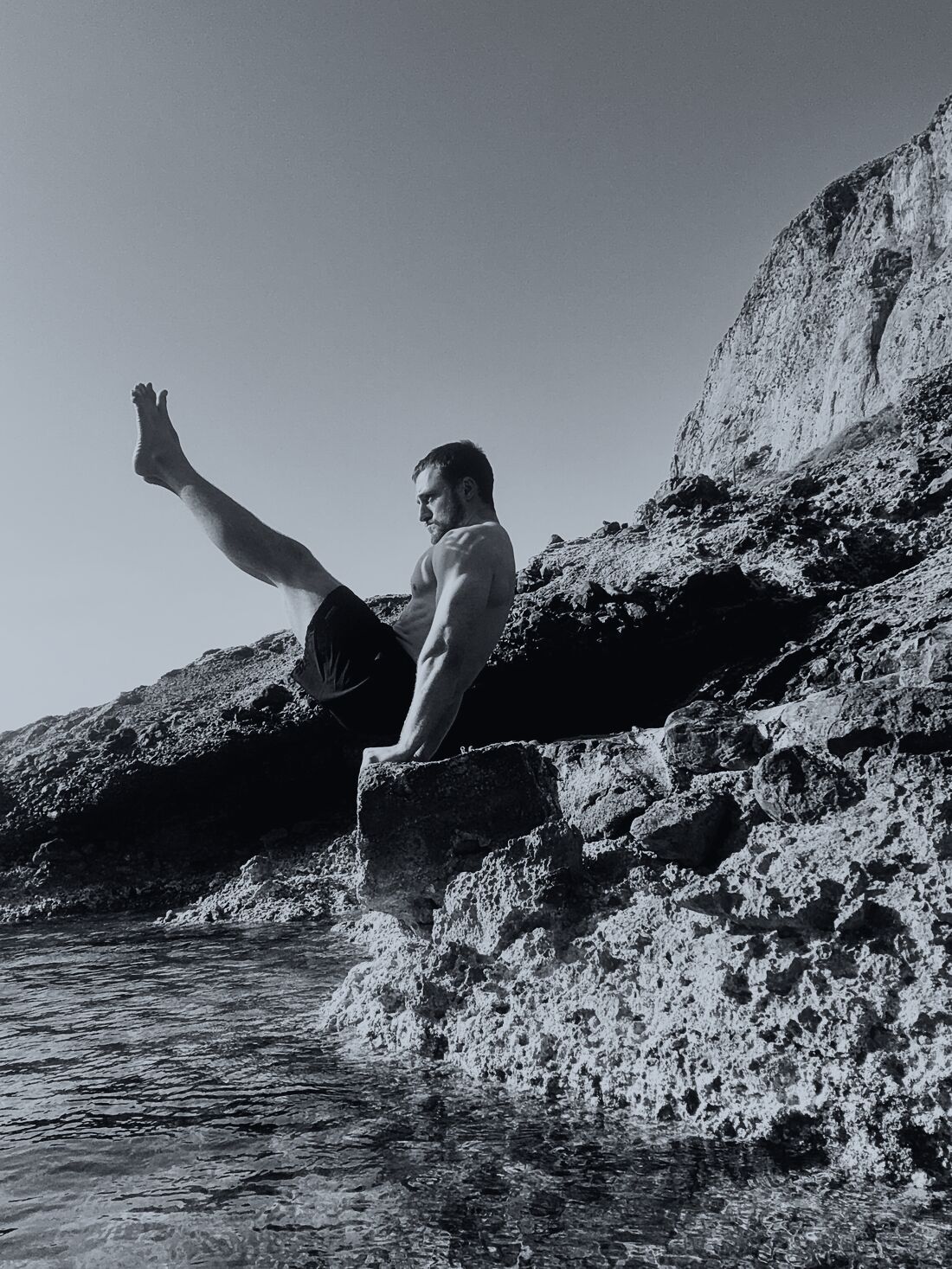 Holding a V-sit on a limestone outcrop above the sea.